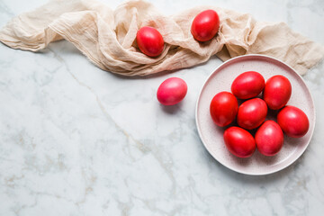 Red Easter Eggs on a White Plate on a Marble Tabletop, Top View