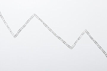 Chain of paperclips mimicking the shape of a falling data graph.
