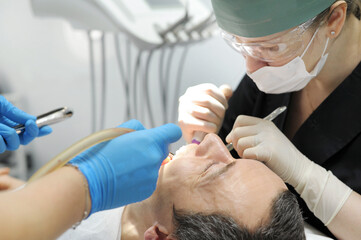 in the dental office, a dentist and his assistant perform an operation to remove high wisdom teeth...