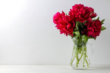 Beautiful bright pink flowers peonies in a jug on a light background. space for text
