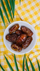 Pile of sweet dried dates in white plate. Popular product for boosting immunity.