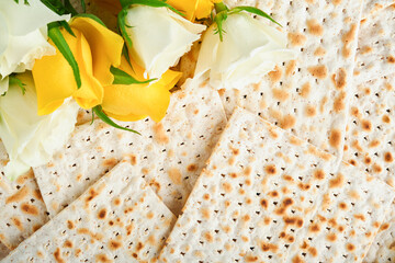 Passover celebration concept. Matzah, red kosher, white and yellow roses and walnut. Traditional ritual Jewish bread matzah, kippah and tallit on old background. Passover food. Pesach Jewish holiday.