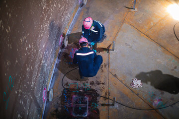 Male worker inspection vacuum test bottom plate tank petrochemical steel weld leak spot light internal