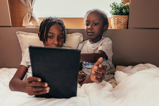 Content African American children watching movie on bed