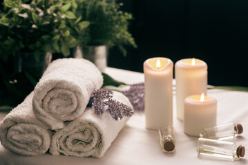 Spa still life with aromatic candles,oils and towel. Dark background