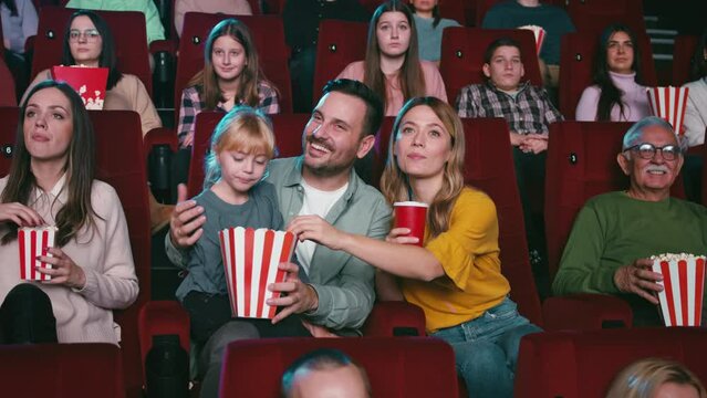 Cheerful family watching movie in theater.