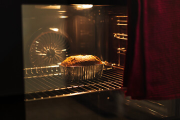 Chocolate cake in backing dish backing in oven at home.