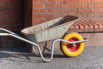 wheelbarrow on the ground in front of brick wall