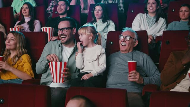 Grandfather, son and granddaughter in movie theater.