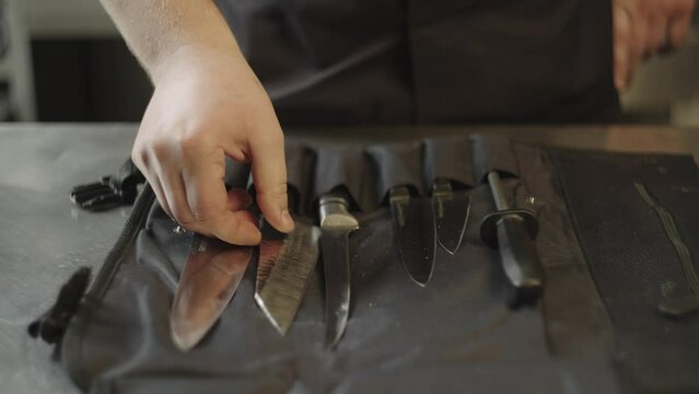 Caucasian male chef selects a slicing knife from his set. Professional knives for cooking in a restaurant, slicing products. High quality 4k footage