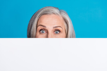 Photo of aged person half face peeking behind empty space blank isolated on blue color background