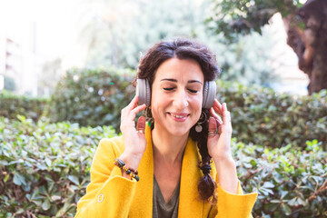 Smiling woman holds headphones over her head