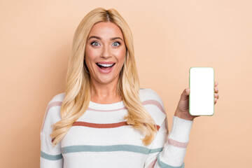 Naklejka premium Photo of nice impressed woman with curly hairstyle striped long sleeve hold phone showing display isolated on pastel color background