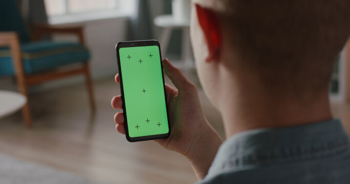 Man using a mobile phone with chroma key green screen, watching a video or having an online conference - technology, communications concept close up 