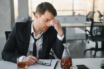 Alcoholism at work. Tired employee drinking alcohol at workplace, can not handle stress.