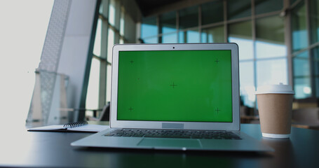 Close up shot of laptop green chroma key screen in bright office room. Computer with mock up display set for work in office - technology, business and office 