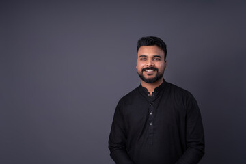 Smiling an with dark hair with mustache and beard portrait on gray background. Horizontal banner empty template gray copy space. Pakistani young man in traditional black shirt clothes