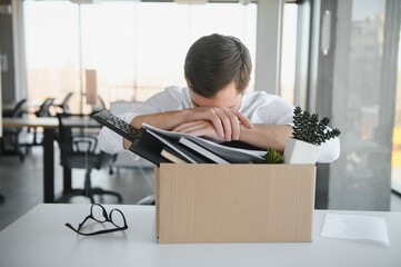 business, firing and job loss concept - fired male office worker with box of his personal stuff.