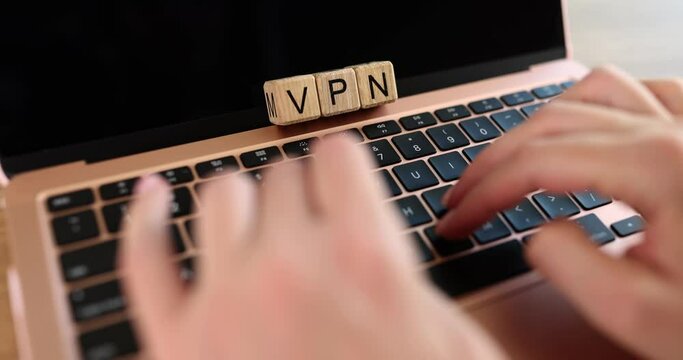 Wooden cubes with letters VPN user is working on laptop
