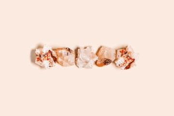 Flat lay bright beige quartz crystals on peach color background. Magic and healing crystal, gem stone, alternative medicine concept. Top view natural gemstone rock, quartz mineral