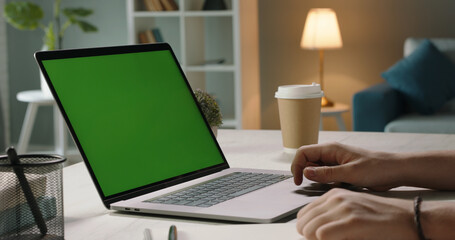 Close up shot of hands of freelancer working with chroma key green screen laptop, using trackpad...