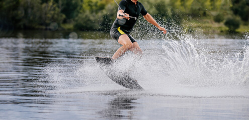 wakeboarder riding on lake behind boat in spray of water
