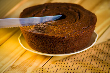 Cutting a homemade chocolate cake on wooden table
