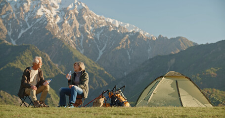 Happy smiling senior couple of tourist enjoy the fresh air in the mountains. Attractive white...