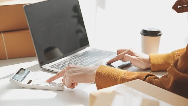 Fashion designer l young asian woman working using laptop, tablet and smiling while standing in workshop Responding on business