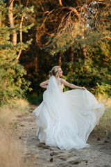 Fototapeta na wymiar bride blonde girl with a bouquet in the forest