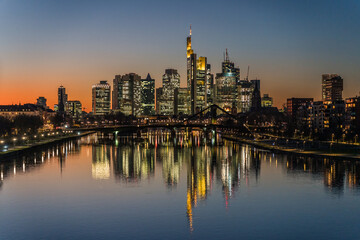 Plakat illuminated skyline at night reflecting in the river