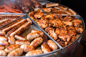 Tasty hot grilled sausages, chicken wings and barbecue in street market ready to eat