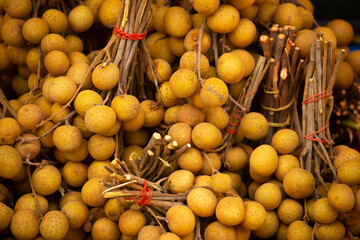 Longan fruit close-up as a background. The Dragon Eye Harvest is in a pile on the counter. Fresh tropical fruits. Dimocarpus longan, Central Thailand