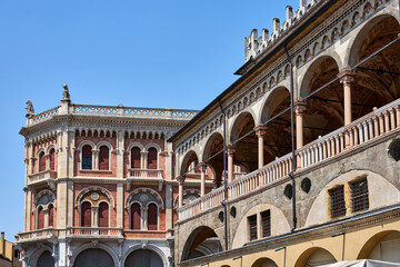 Fototapeta na wymiar Fragment of the colonnade of the medieval Palazzo della Ragione market hall against the background of the facade of a historic tenement house in the city of Padua
