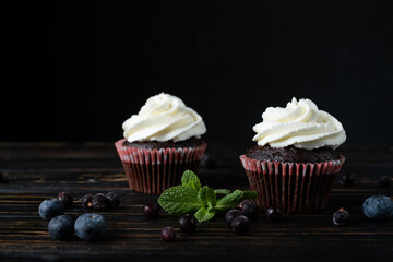 two delicious chocolate cakes with berries and mint on a dark background