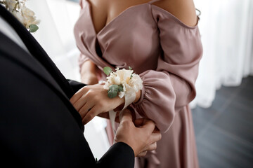 Groom corrects bride boutonniere on hand at their wedding close-up details
