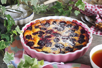 Blue plum clafoutis (flan), icing sugar dressing and cup of tea - 571992642