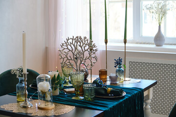 The luxury served table indoors in green colors. Dark wooden table, beautiful evening restaurant with luxury decor