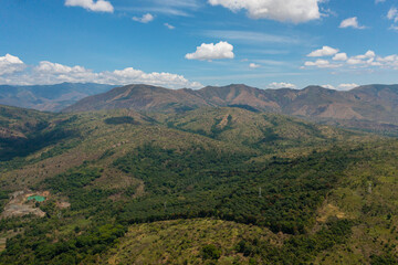 Aerial view of Mountains covered rainforest, trees and blue sky with clouds. Philippines.