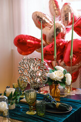Festive table setting in dining room decorated for Valentine's Day. Decorated table for two with large heart shaped balloons