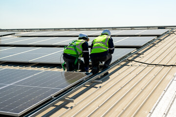 Professional technicians installing solar panels on rooftop of plant, Workers checking and...