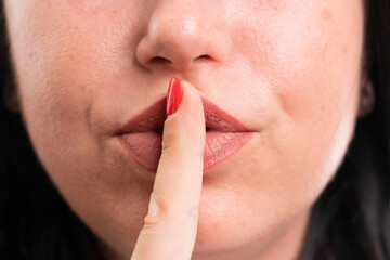 Close-up of shush gesture with finger over mouth made by woman