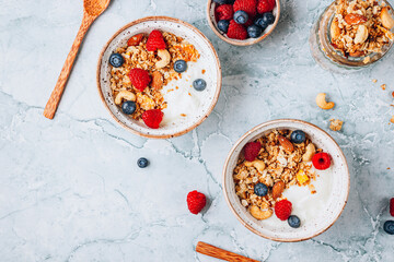 Healthy brakfast with yogurt and baked granola with berries in two small bowls.