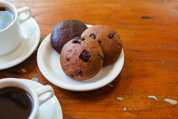 Three delicious organic chocolate chip cookies on a white plate side view. Oatmeal biscuits for breakfast with coffee