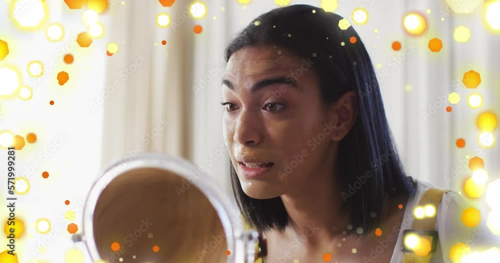 Canvas Prints Animation of light spots over biracial woman applying make-up