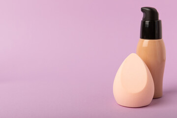 Beauty blender and foundation, bb cream or concealer on a colored background. Bright sponges for...