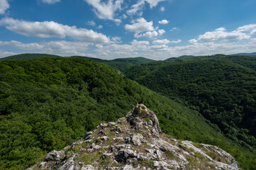 Lookout with a rock in the foreground of green leafy forests and hills in the Slovak Little Carpathian Mountains