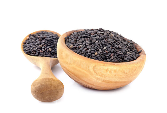Black cumin on white background closeup in wooden bowl.
