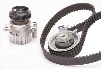 Automobile spare part. Close up repair kit: Timing belt with rollers, Tensioner pulley, Deflection pulley, Two rollers, Water pump and bolts on white background. 