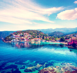 Fototapeta premium Beautiful landscape with bay and colorful buildings on the background of picturesque clouds in the town of Asos, Greece, Kefalonia. Wonderful exciting places.